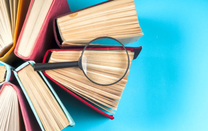 A group of nondescript books placed on a table with a magnifying glass